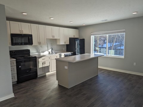 an empty kitchen with white cabinets and black appliances